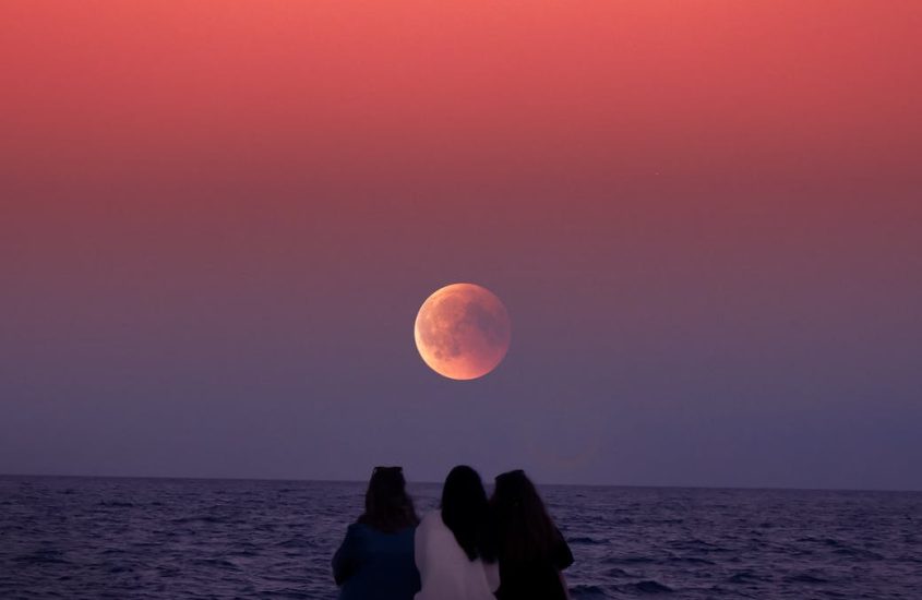 women sitting on rock infront of ocean